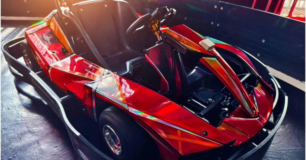 A red holographic go-kart is parked on the track. The sun is shining through a window in the background.