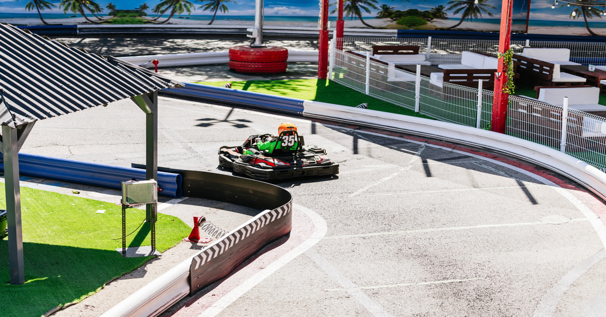 A person is driving a black go-kart on an outdoor track. The go-kart features the number 35 on the back.